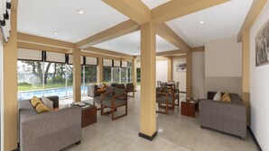 A spacious indoor area with a pool view, multiple seating arrangements, and a high ceiling with exposed beams. - Melheim Kandy Villas (Kandy)