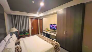 Ein Hotelzimmer mit Bett, Schreibtisch, Fernseher und Kleiderschrank.