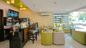 A modern bar area with a counter, seating, and a TV screen. - 88 Courtyard Hotel (Pasay)