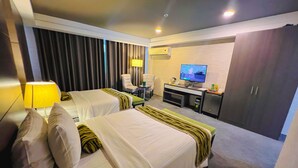 A hotel room with two beds, a desk, a chair, a TV, and a wardrobe. - 88 Courtyard Hotel (Pasay)