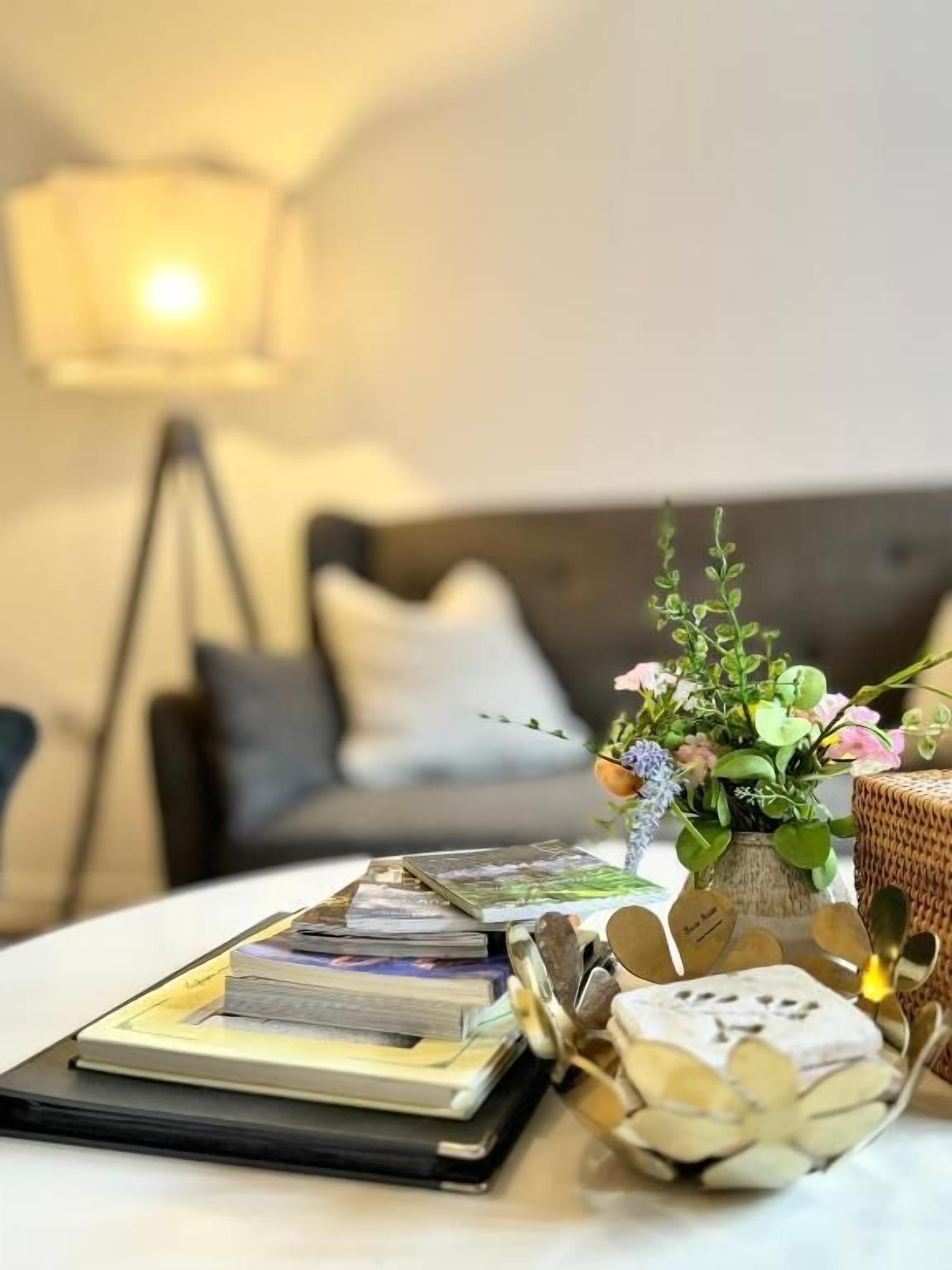 A neatly arranged table with books, a small vase with flowers, and a decorative item.