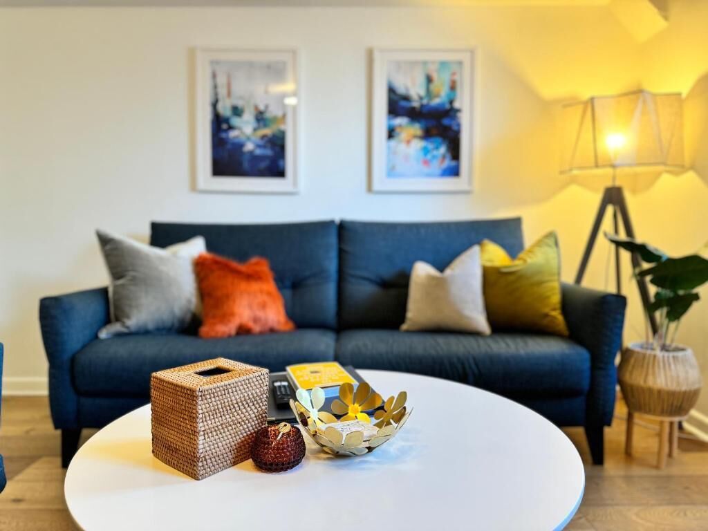 A living room with a dark blue sofa, a white coffee table, and two framed abstract paintings on the wall.