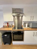 A compact kitchen with a stainless steel range hood, a built-in oven, and a microwave.