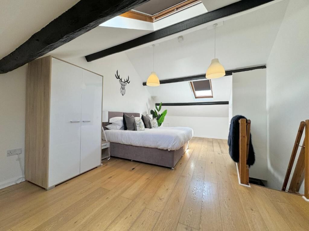 Een slaapkamer met een bed, een kledingkast, een dakraam en een hangplant.
