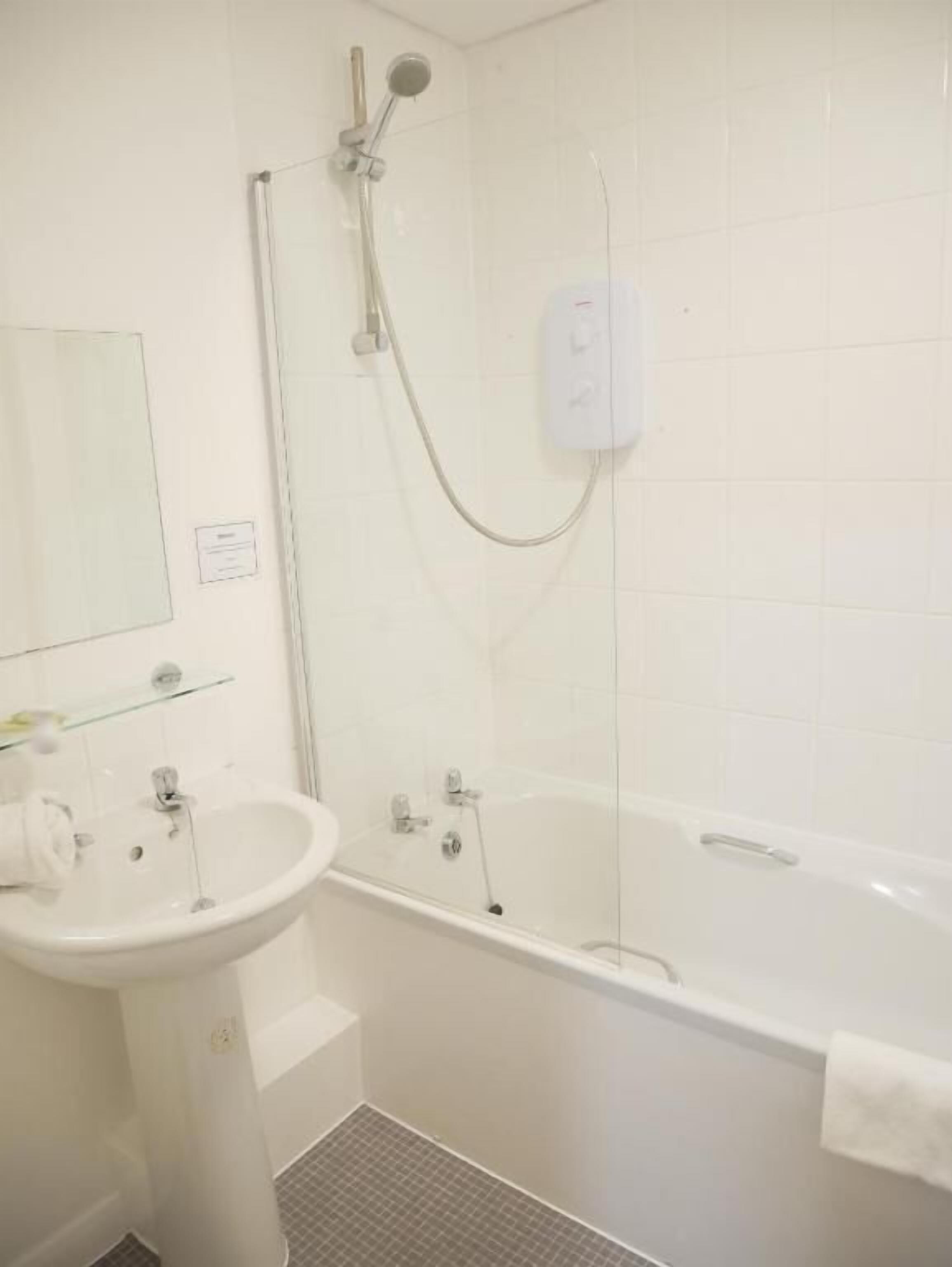 A bathroom with a sink, mirror, shower, and bathtub.