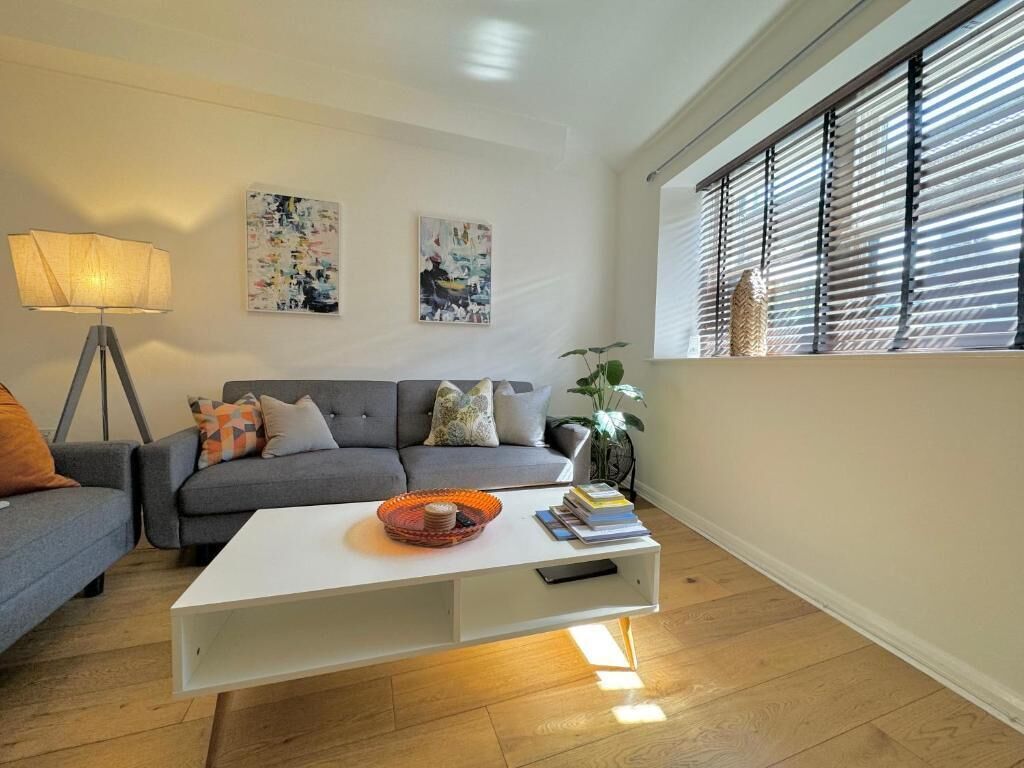 Ein Wohnzimmer mit grauem Sofa, weißem Couchtisch und einer Stehlampe.