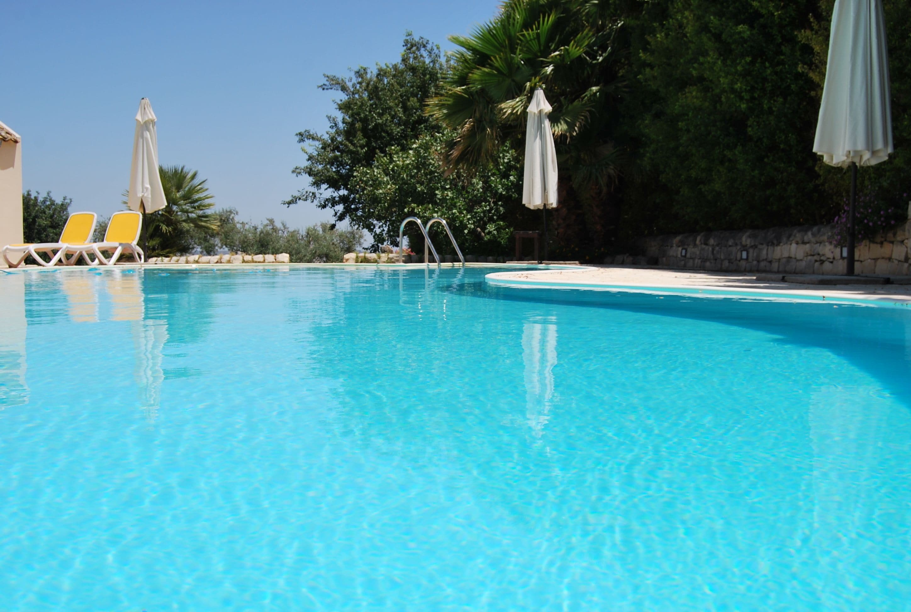 Una piscina cristallina con lettini e ombrelloni.