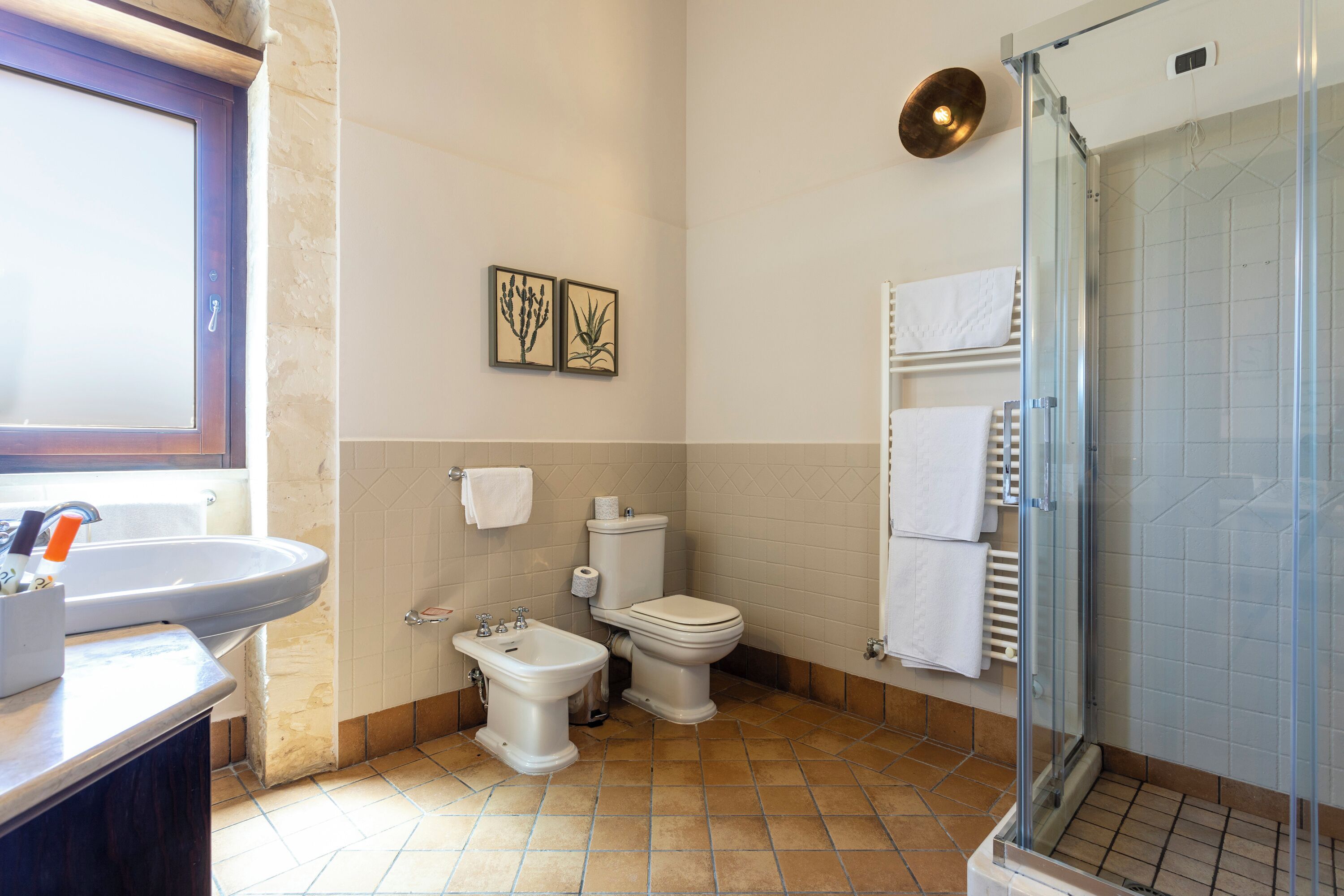 Un baño con lavabo, bidé, inodoro y cabina de ducha de vidrio.