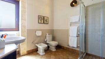 Un baño con lavabo, bidé, inodoro y cabina de ducha de vidrio.
