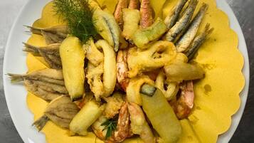 A plate of fried seafood including shrimp, squid, and fish, garnished with dill.