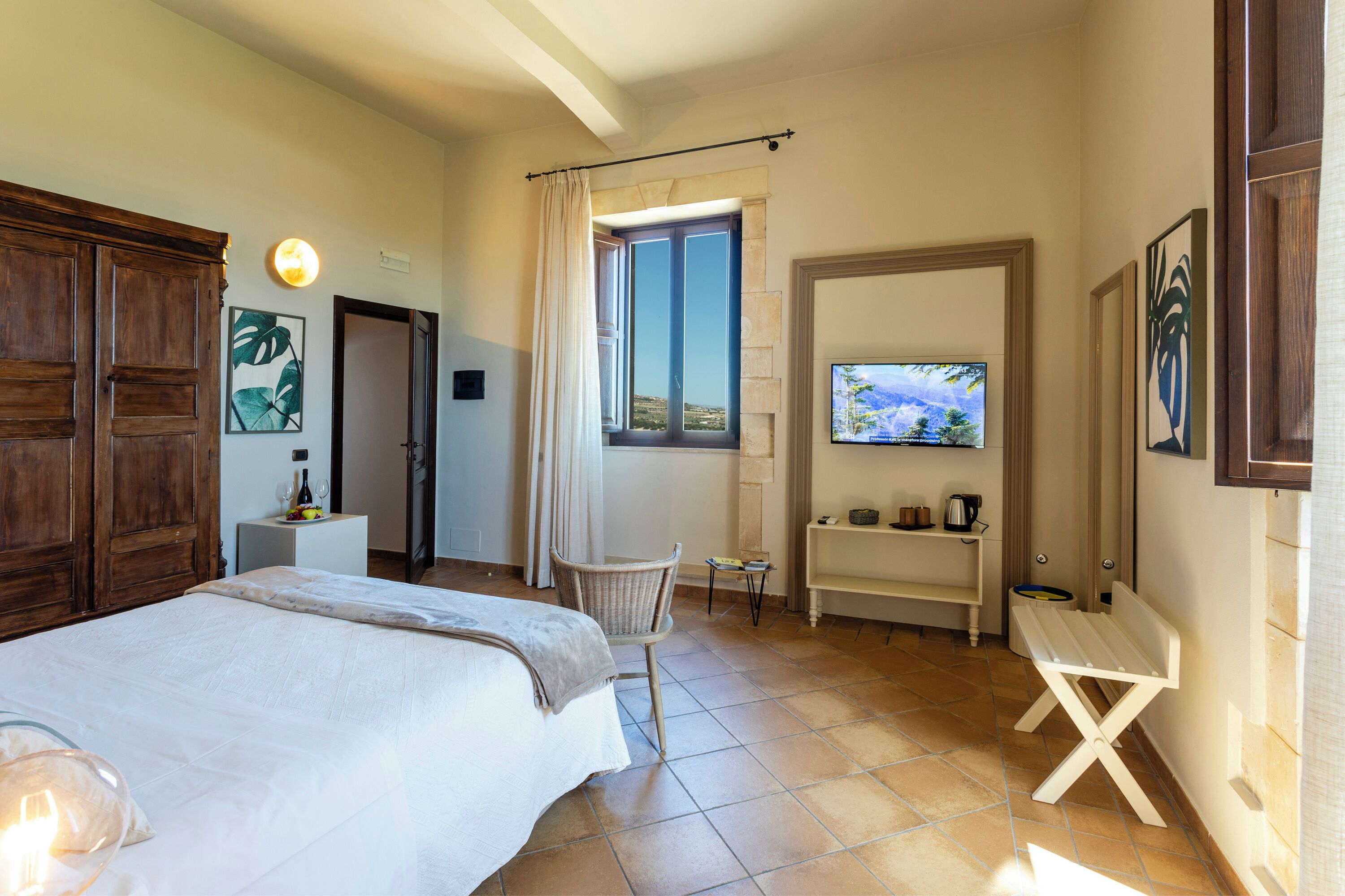 A hotel room with a bed, a chair, a TV, a window, and a view of the outdoors.