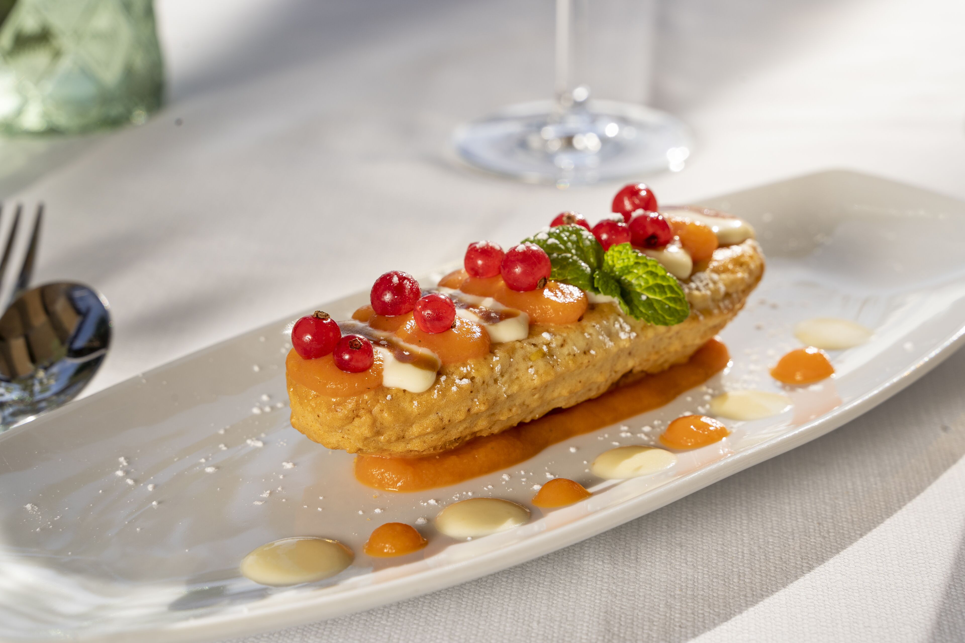 A dessert on a white plate with a fork and spoon beside it.