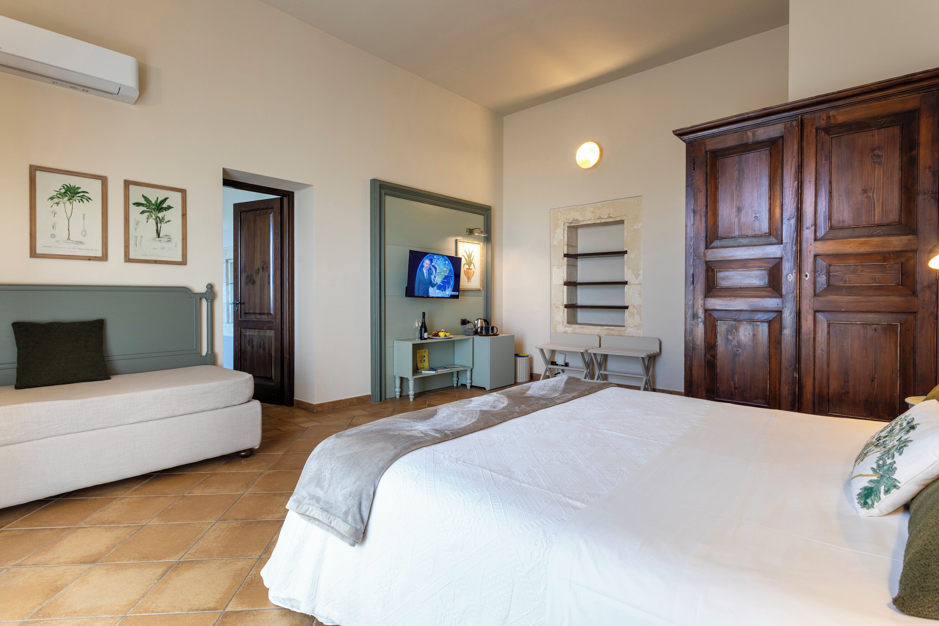 Une chambre d’hôtel comprenant un grand lit, un canapé, un bureau avec une chaise, une télévision et une armoire.