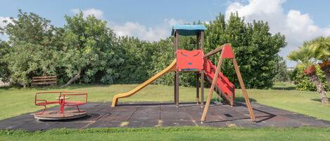 Un parque infantil con tobogán, estructura para escalar y un carrusel.