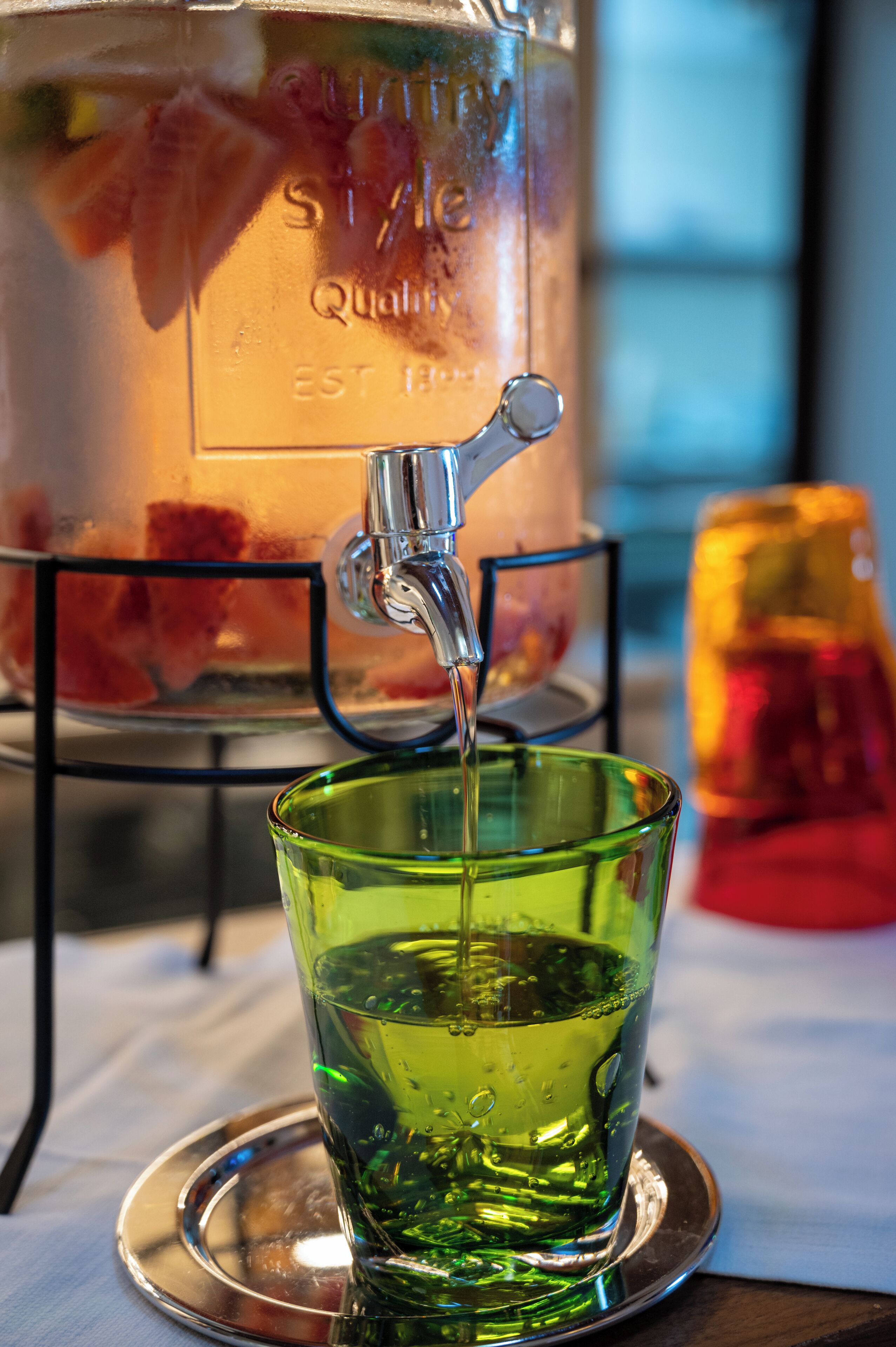 A glass of green liquid being poured from a tap into a glass.
