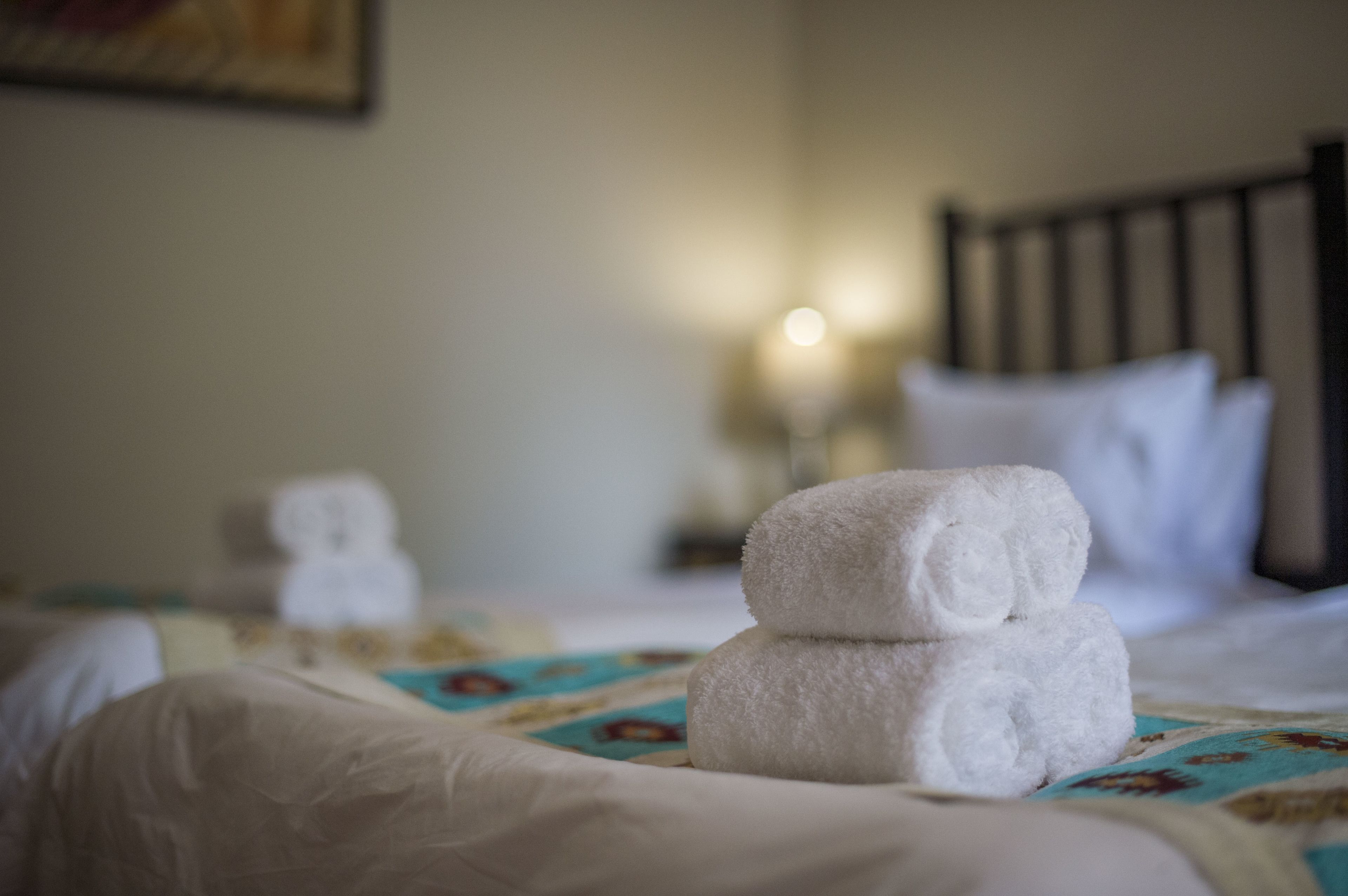 Una cama bien hecha con sábanas blancas y una colcha de estampado floral.
