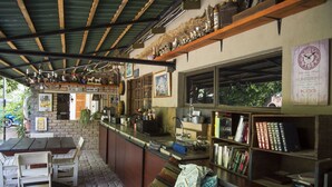 A cozy bar area with a wooden counter, bookshelves, and a stone wall. - Tsumeb Backpackers & Safari (Tsumeb)