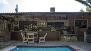 A bar area with a pool, outdoor seating, and a brick building with various decorations. - Tsumeb Backpackers & Safari (Tsumeb)
