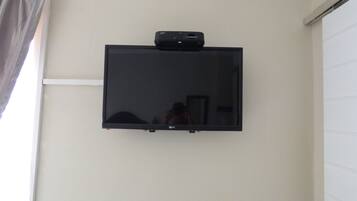 A flat-screen TV mounted on a wall with a cable box above it.