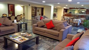 Un vestíbulo amplio con sofás, una mesa baja y una zona de comedor con sillas y mesas.
