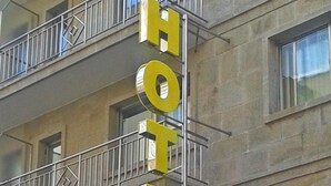 Un letrero de hotel con la palabra 'HOTEL' en letras amarillas grandes y 'WINDSOR' en letras amarillas más pequeñas debajo.