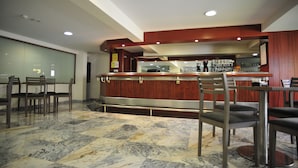 Un vestíbulo de hotel con piso de mármol, mostrador de recepción de madera y sillas modernas.