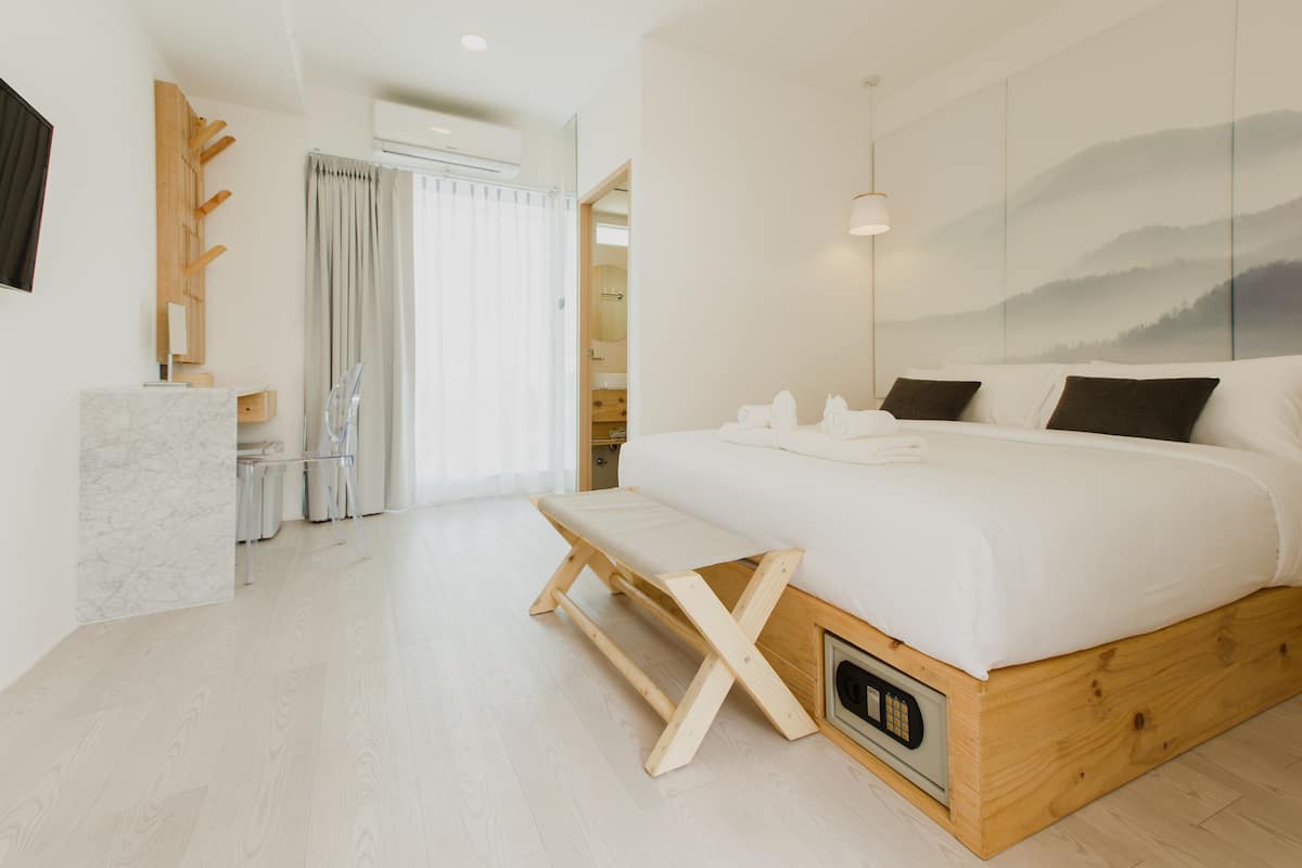 Un dormitorio moderno con una cama grande, cabecera de madera y un banco.