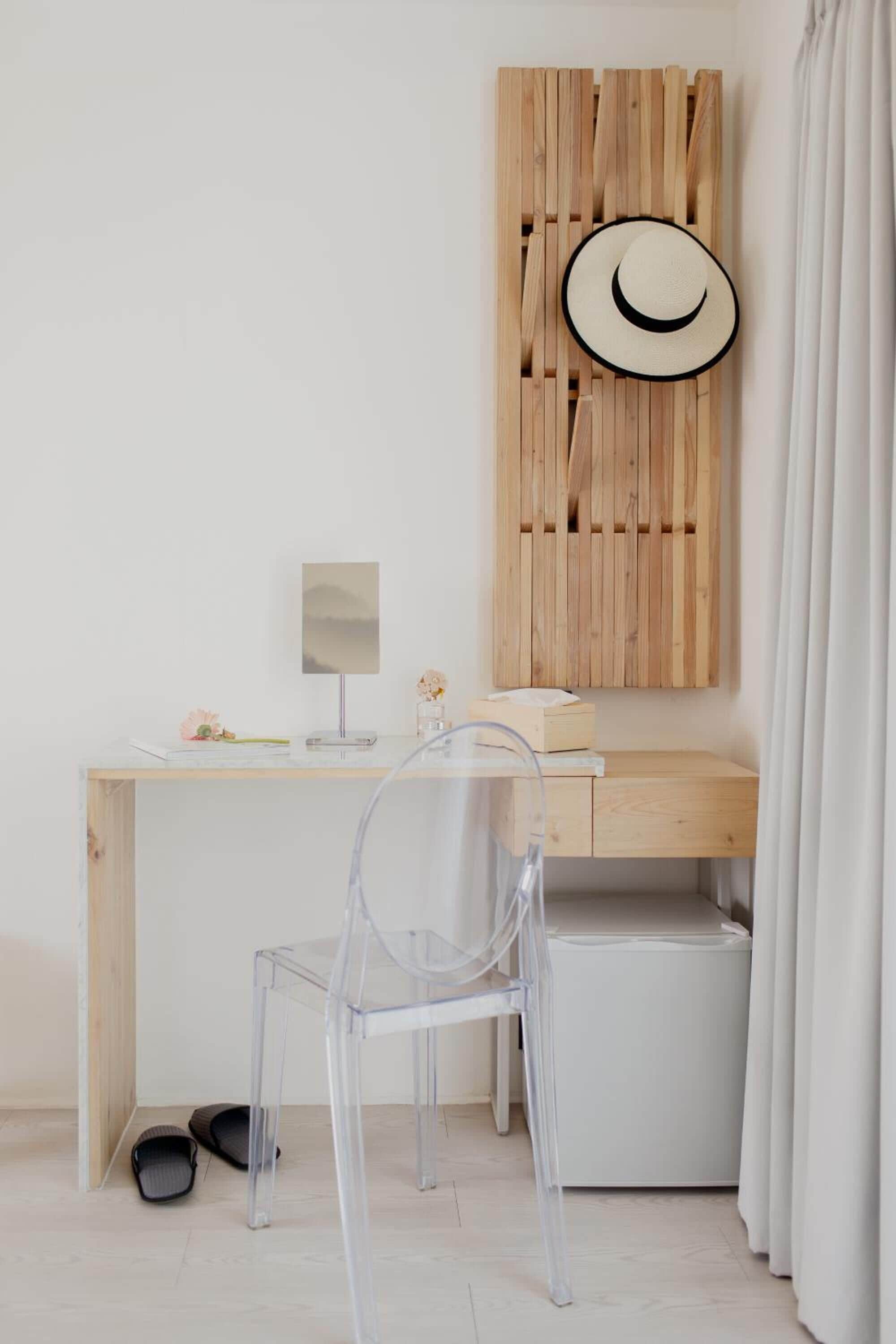 A minimalist workspace with a wooden desk, a clear chair, and a computer.