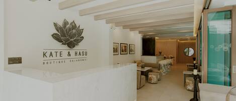 A modern boutique hotel reception area with a minimalist design, featuring a reception desk, seating area, and artwork on the walls.