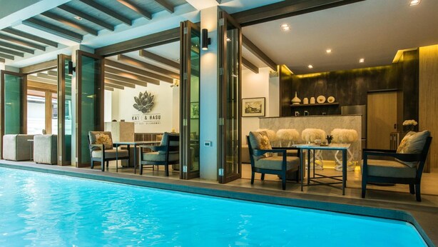 Un vestíbul d'hotel modern amb piscina, zona de seients i taulell de recepció.