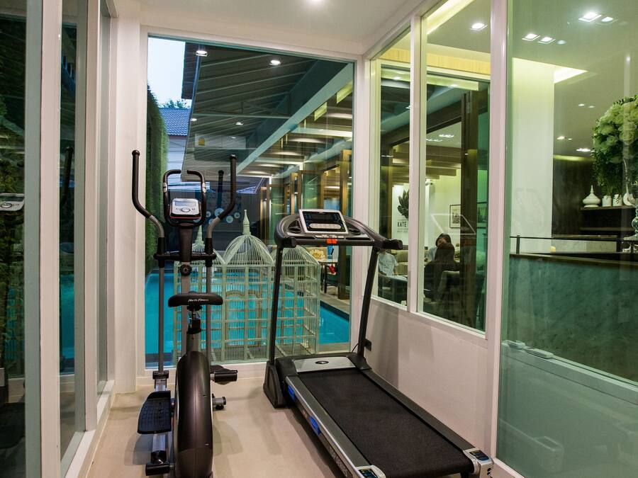 Un gimnasio moderno de hotel con cinta de correr, elíptica y bicicleta estática, con vistas a una zona de piscina.