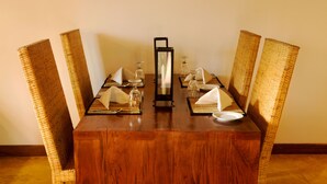 A dining table set with wicker chairs, a central mirror, and glassware. - Sigiriya Lodge - Hostel (Avudangawa)