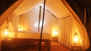 A tented accommodation with a bed, pillows, a bench, and two lanterns. - Sigiriya Lodge - Hostel (Avudangawa)