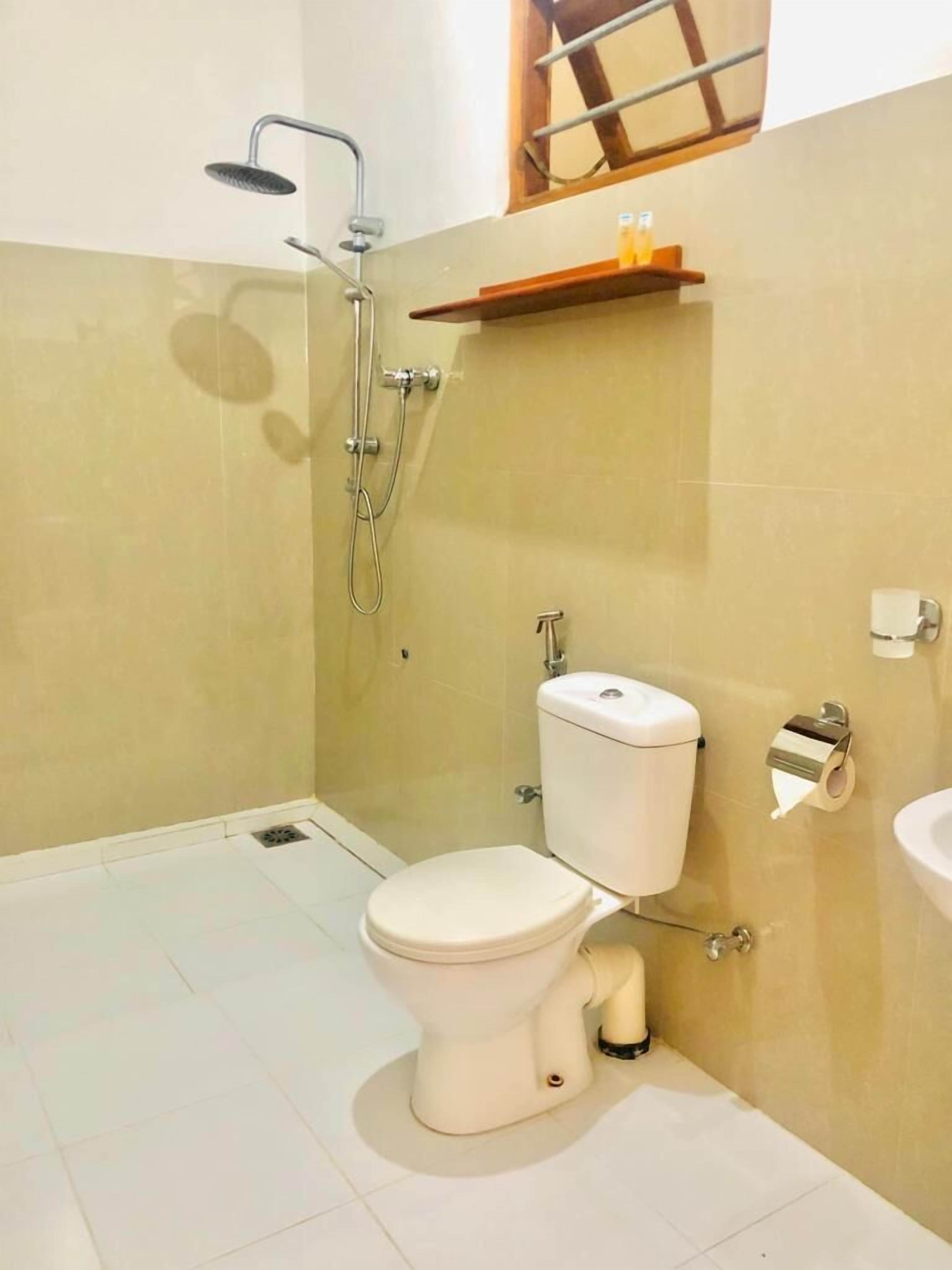 A small bathroom with a toilet, a shower, and a sink.
