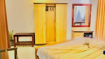 Una habitación de hotel con cama, armario de madera, una mesita y un espejo.