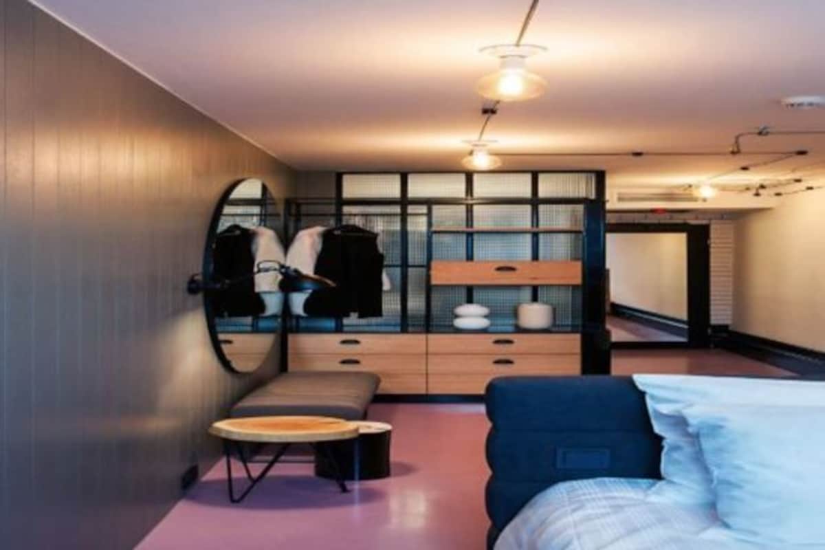 A modern bedroom with a bed, a seating area, a vanity with a mirror, and a wardrobe.
