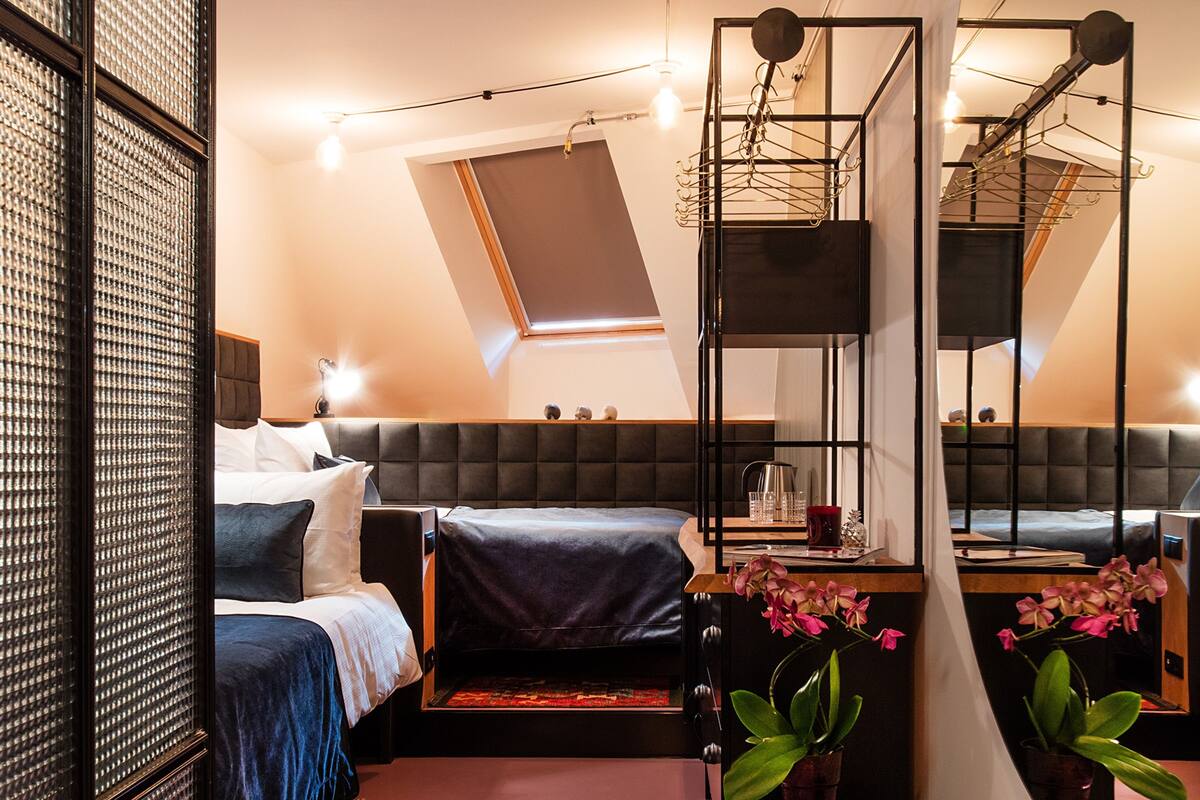 A modern bedroom with a loft bed, a large mirror, and a small wooden stool.