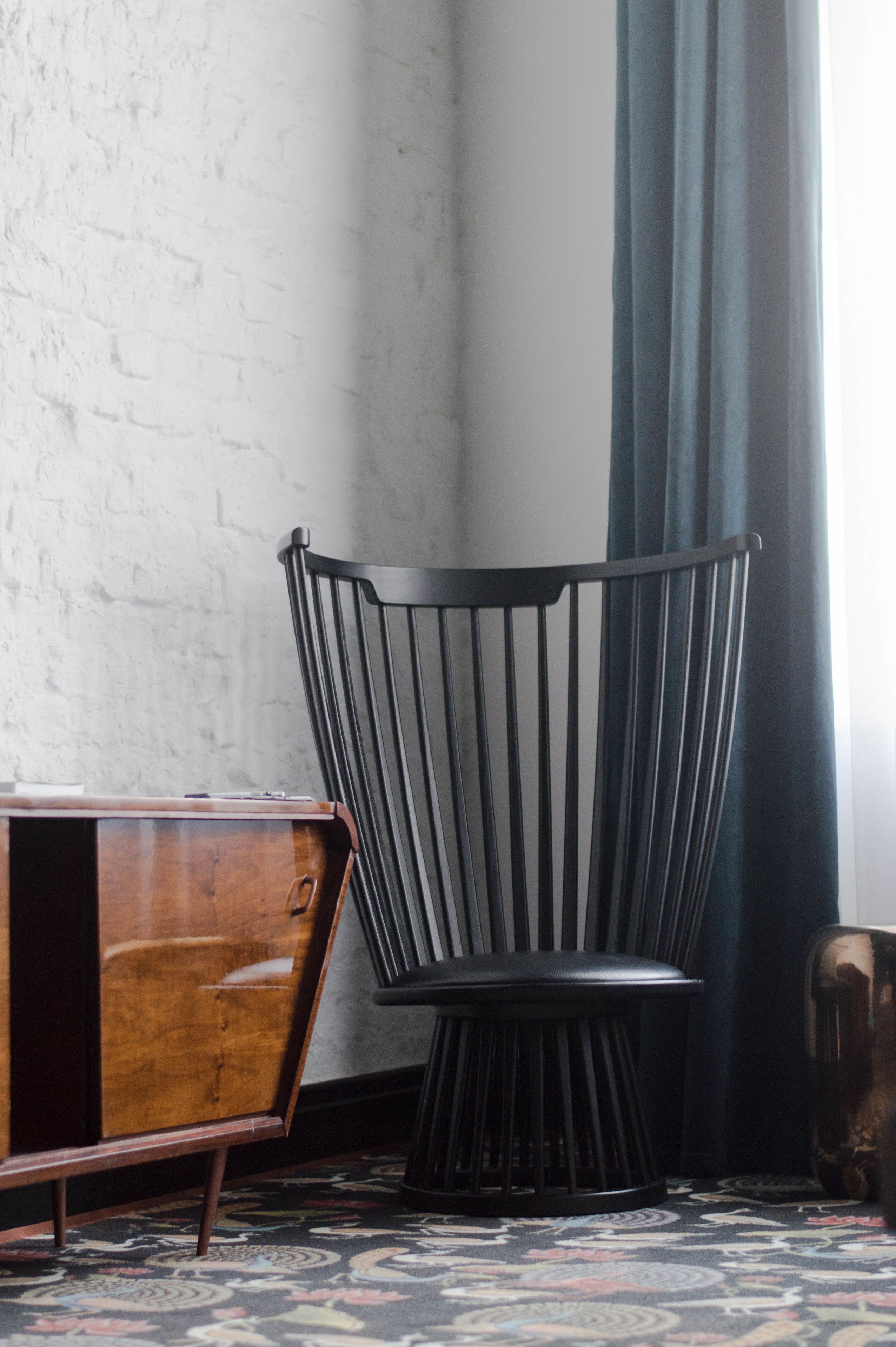 A corner with a black metal chair, a wooden cabinet, and a patterned carpet.