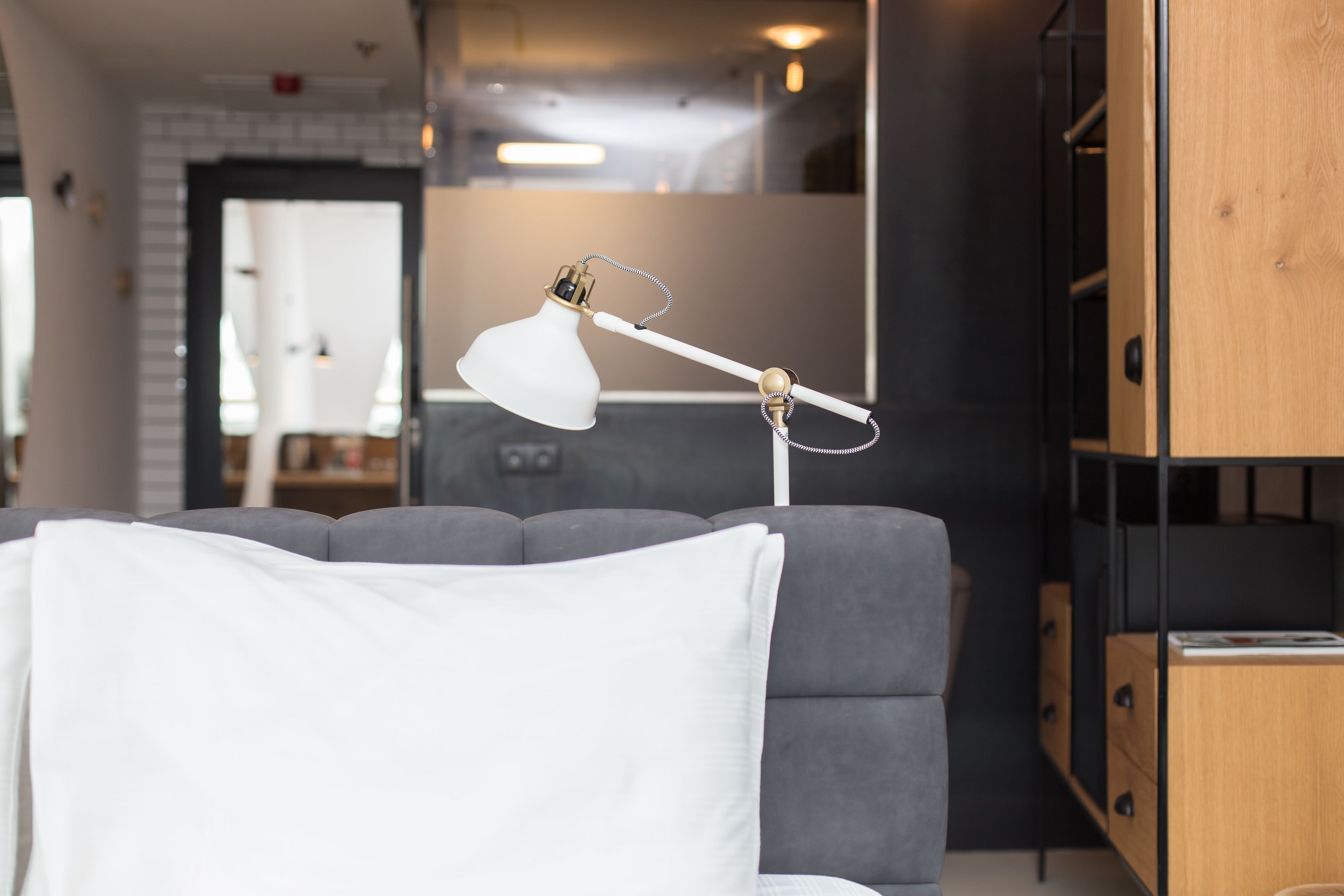 Una sala moderna con un sofá gris, una lámpara blanca y un mueble de madera.