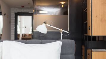 Una sala moderna con un sofá gris, una lámpara blanca y un mueble de madera.
