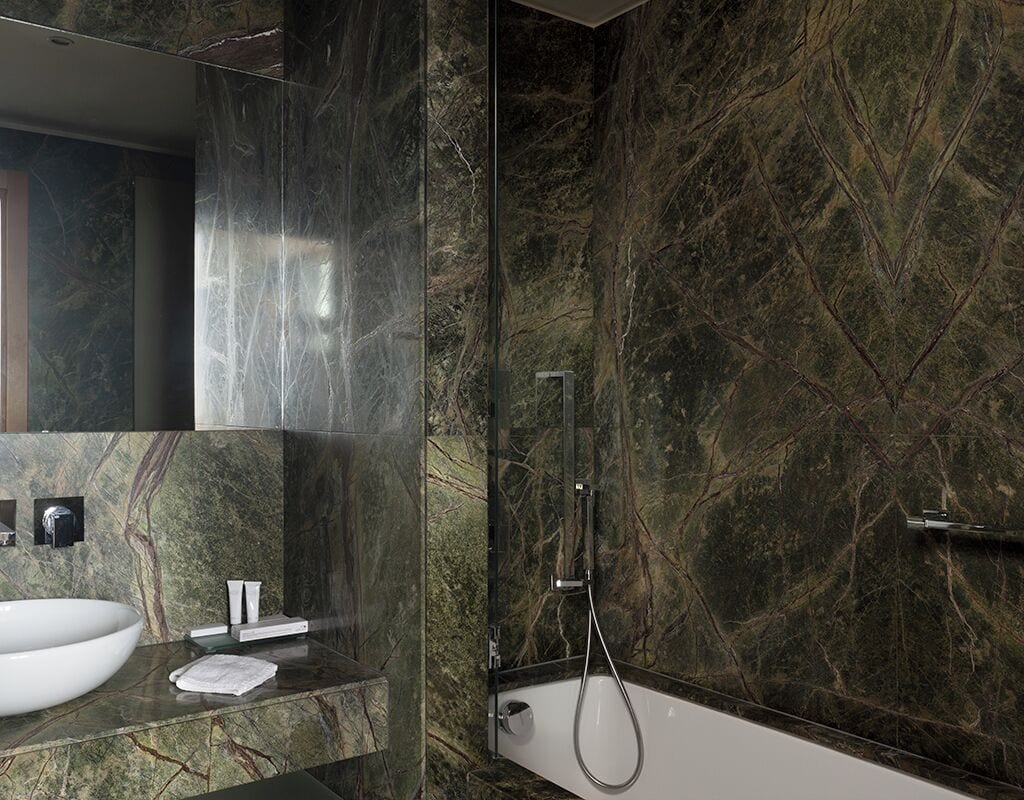 Ein modernes Badezimmer mit einem großen weißen Waschbecken, einem Spiegel und einer Dusche inklusive Duschbrause.