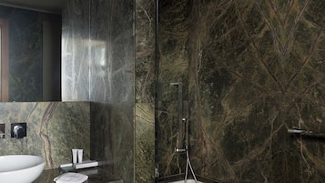 Ein modernes Badezimmer mit einem großen weißen Waschbecken, einem Spiegel und einer Dusche inklusive Duschbrause.