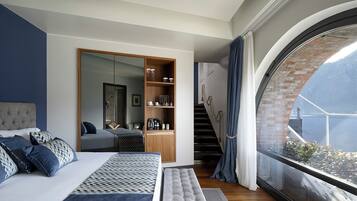 Un dormitorio moderno con una cama grande, un armario empotrado, un área de descanso y un amplio ventanal con vistas al exterior.