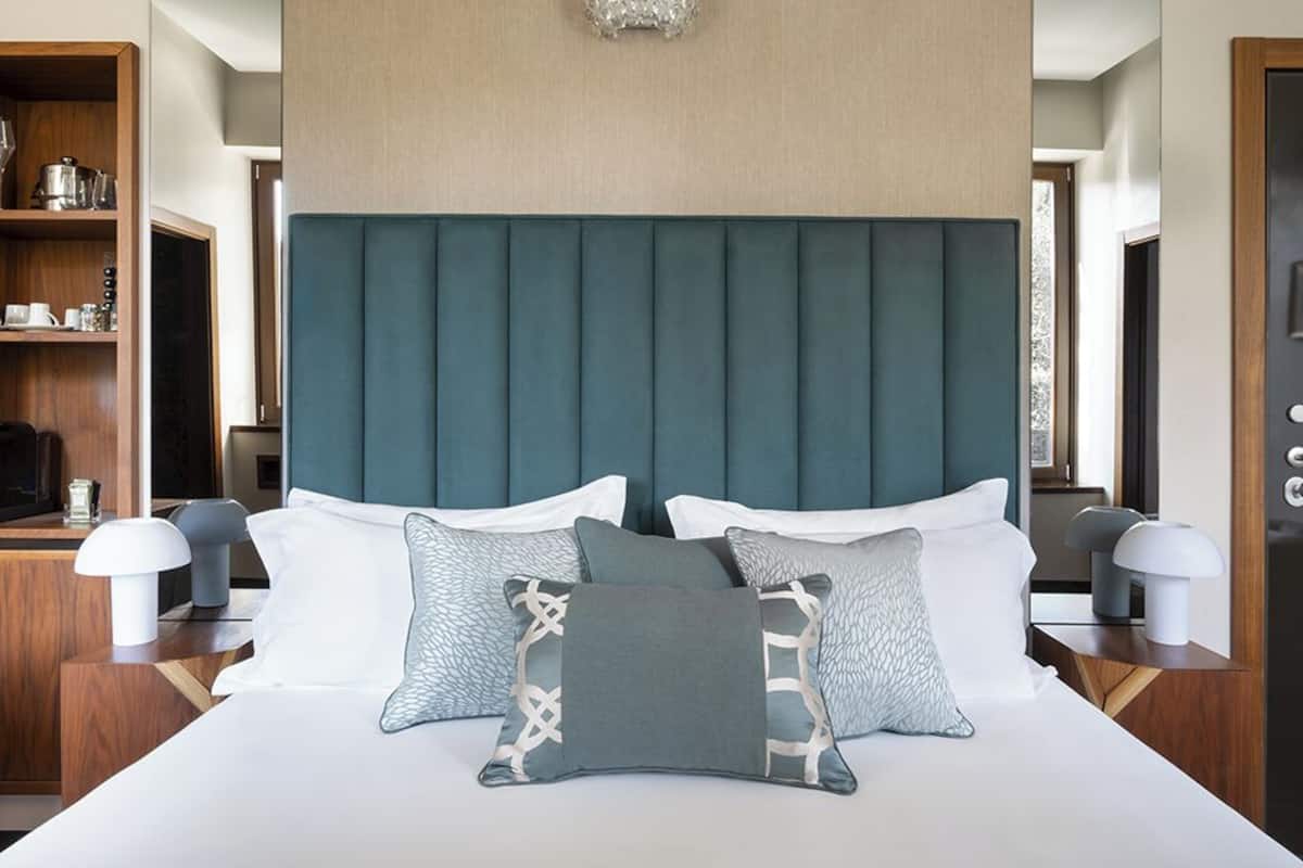 A hotel room with a large bed, a wooden nightstand, a bedside table, and a headboard.