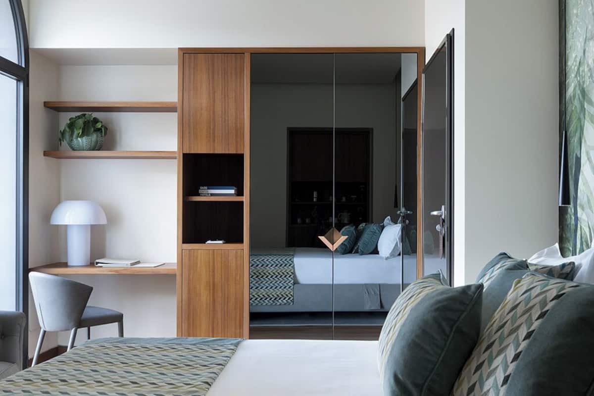 A modern bedroom with a bed, a desk, and a wardrobe.