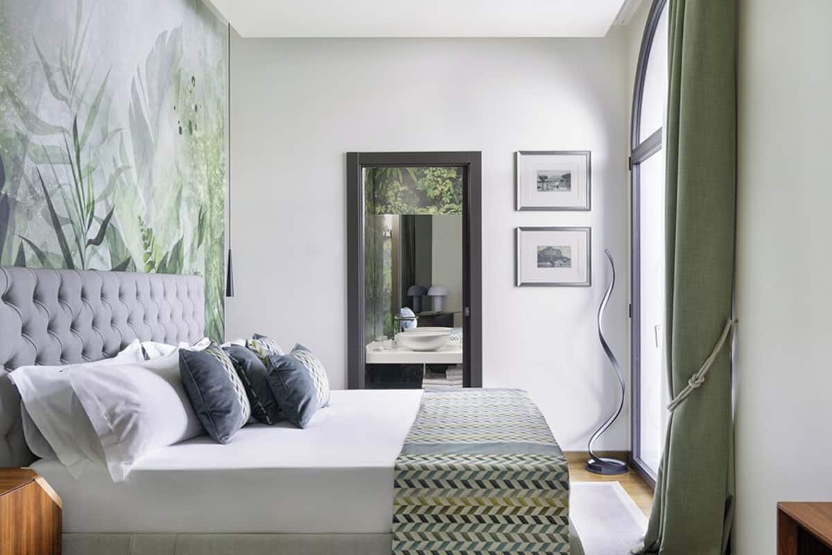 A bedroom with a large bed, a mirror, and a view of the bathroom.