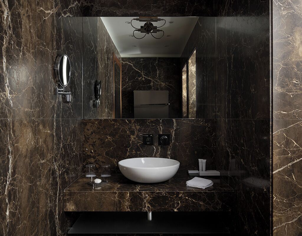 A modern bathroom with a large white vessel sink, a mirror, and a ceiling light fixture.