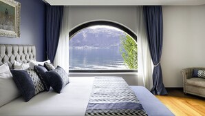 A bedroom with a large bed, a view of a lake, and a window with curtains.