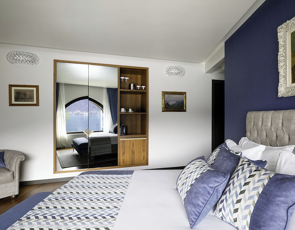 A bedroom with a large bed, a wardrobe with a mirror, and a view of a balcony.