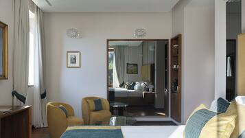 Una moderna camera d'albergo con un letto grande, una zona salotto con una poltrona, una scrivania e uno specchio.